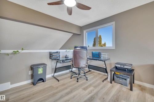 This versatile area features light-toned flooring, a window offering views of trees and blue sky, and a ceiling fan - 8807 31 Avenue, Edmonton, AB - Indoor Photo Showing Office