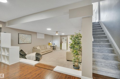 The property features a spacious living area with both carpeted and hardwood flooring, neutral-toned walls, and recessed lighting - 8807 31 Avenue, Edmonton, AB - Indoor Photo Showing Other Room