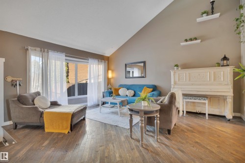 The property features a spacious living area with sloped ceilings, hardwood flooring, and large windows providing natural light - 8807 31 Avenue, Edmonton, AB - Indoor