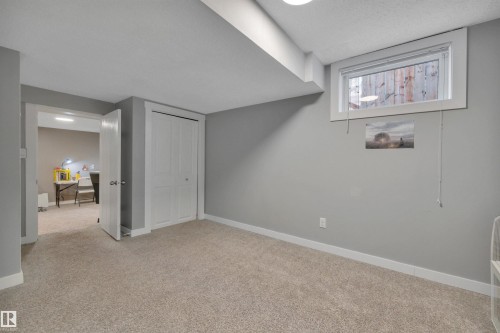This room features neutral-toned carpet, light gray walls, and white trim - 8807 31 Avenue, Edmonton, AB - Indoor Photo Showing Other Room