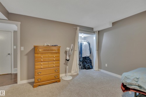 The room features carpeted flooring, neutral wall paint, and a built-in closet with a curtain enclosure - 8807 31 Avenue, Edmonton, AB - Indoor