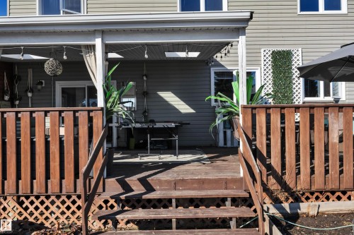 The property features an exterior deck with wooden stairs and railings, leading to a covered patio area - 8807 31 Avenue, Edmonton, AB - Outdoor