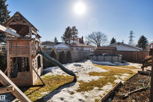 The property features a fenced yard with a wooden play structure and an above-ground pool - 8807 31 Avenue, Edmonton, AB - Outdoor