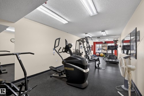 Fitness room featuring a variety of exercise equipment, rubber flooring, and bright overhead lighting - 106 15499 Castle Downs Road, Edmonton, AB - Indoor Photo Showing Gym Room