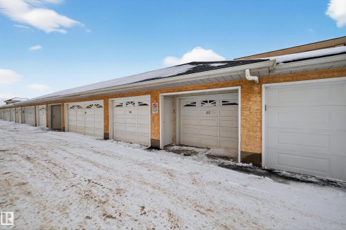 The property includes dedicated garage spaces with white overhead doors, providing convenient parking or storage options - 106 15499 Castle Downs Road, Edmonton, AB - Outdoor With Exterior