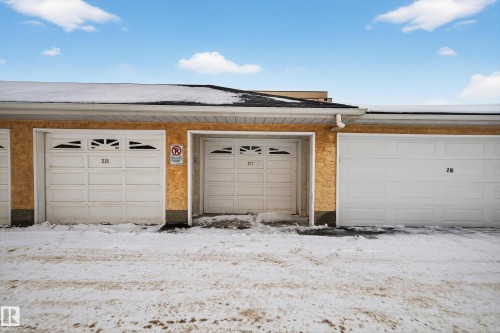 Property features a row of garages with white doors and numbers - 106 15499 Castle Downs Road, Edmonton, AB - Outdoor With Exterior
