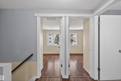 Interior view featuring light gray and beige walls, wood-look flooring, and a white door with a silver handle - 3301 139 Avenue, Edmonton, AB - Indoor Photo Showing Other Room