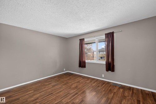 This room features rich wood-style flooring, neutral painted walls, and a window with curtains - 3301 139 Avenue, Edmonton, AB - Indoor Photo Showing Other Room