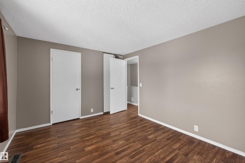 This room features rich wood-look flooring and neutral-toned walls, providing a versatile backdrop for personalization - 3301 139 Avenue, Edmonton, AB - Indoor Photo Showing Other Room