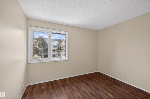 The room features wood-style flooring and a large window providing views of the exterior - 3301 139 Avenue, Edmonton, AB - Indoor Photo Showing Other Room