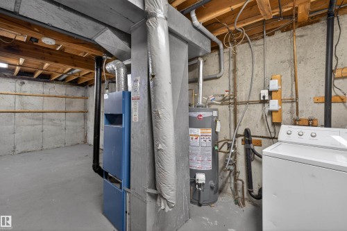 The property features a utility area with a water heater, a furnace, and a washing machine - 3301 139 Avenue, Edmonton, AB - Indoor Photo Showing Basement