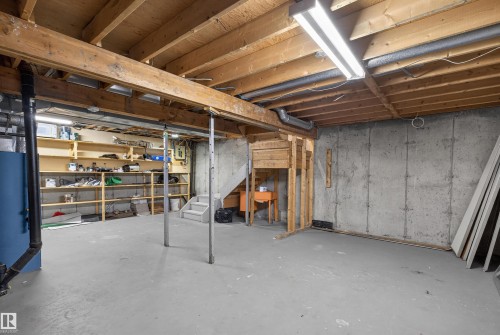 The property features a spacious unfinished basement with concrete walls and flooring, exposed wooden beams, and built-in shelving for storage - 3301 139 Avenue, Edmonton, AB - Indoor Photo Showing Basement