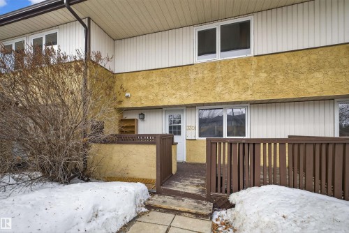 The property features a white door, a brown wooden fence, and multiple windows across two levels - 3301 139 Avenue, Edmonton, AB - Outdoor