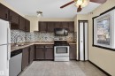 Kitchen featuring brown cabinetry, a tile backsplash, a stainless steel oven and microwave, and tile flooring - 3301 139 Avenue, Edmonton, AB  - Indoor Photo Showing Kitchen With Double Sink 
