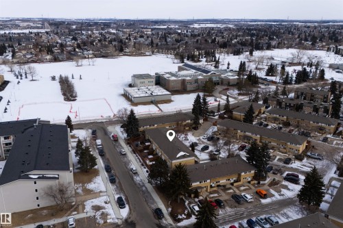 Aerial view of the property and surrounding neighborhood, featuring a large open field, nearby buildings, and residential streets with parked vehicles - 3301 139 Avenue, Edmonton, AB - Outdoor With View