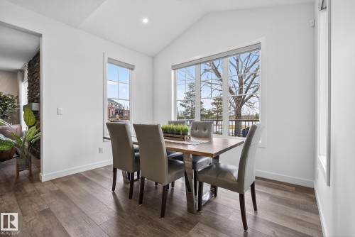 The dining area features wood flooring, large windows providing ample natural light, and a vaulted ceiling - 13 Bilodeau Crescent, Beaumont, AB - Indoor Photo Showing Dining Room