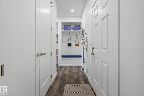 Entryway featuring engineered wood flooring, white paneled doors, and a built-in bench with a blue cushion - 13 Bilodeau Crescent, Beaumont, AB - Indoor Photo Showing Other Room