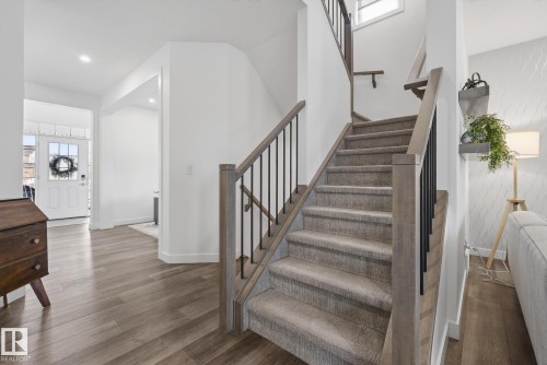 The property features a staircase with carpeted steps and a modern railing with wooden handrails and black balusters - 13 Bilodeau Crescent, Beaumont, AB - Indoor Photo Showing Other Room