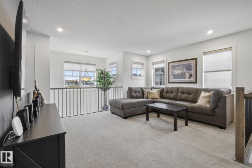 The property features an open loft area with carpeted flooring, white walls, and recessed lighting - 13 Bilodeau Crescent, Beaumont, AB - Indoor Photo Showing Living Room