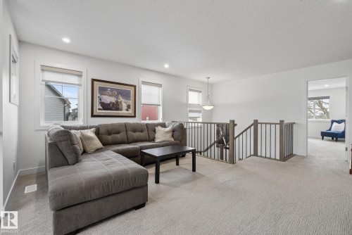 The property features a bright living area with recessed lighting, carpet flooring, and several windows providing natural light - 13 Bilodeau Crescent, Beaumont, AB - Indoor Photo Showing Living Room