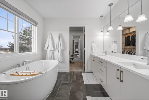 This bathroom features a freestanding soaking tub with an adjacent window, offering natural light - 13 Bilodeau Crescent, Beaumont, AB - Indoor Photo Showing Bathroom