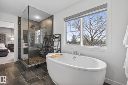 Bathroom featuring a freestanding oval tub, a walk-in shower with a glass enclosure, and a window providing natural light - 13 Bilodeau Crescent, Beaumont, AB - Indoor Photo Showing Bathroom