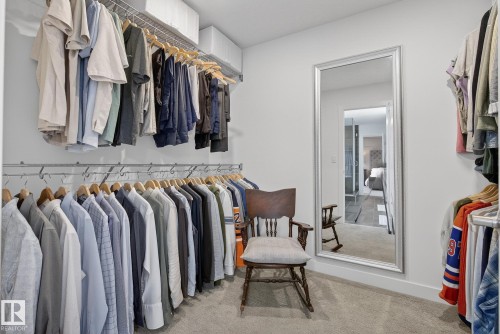 Walk-in closet featuring extensive built-in garment hanging rails and shelves, carpeted flooring, and a full-length mirror - 13 Bilodeau Crescent, Beaumont, AB - Indoor With Storage
