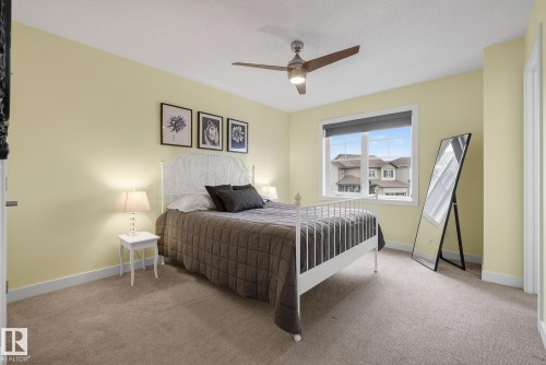 This room features a window providing natural light, a ceiling fan with integrated lighting, and light-colored walls - 13 Bilodeau Crescent, Beaumont, AB - Indoor Photo Showing Bedroom