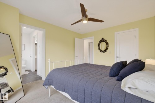 The property features light yellow walls, a ceiling fan with a light fixture, and light-colored carpeting - 13 Bilodeau Crescent, Beaumont, AB - Indoor Photo Showing Bedroom