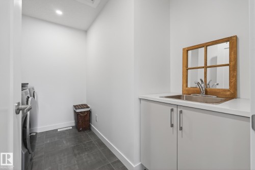 Utility room featuring a built-in sink with a countertop, cabinets, and a tile floor - 13 Bilodeau Crescent, Beaumont, AB - Indoor