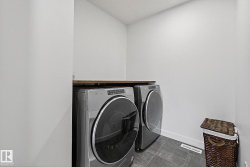 The property features an in-unit laundry area with two large appliances, a countertop, and tiled flooring - 13 Bilodeau Crescent, Beaumont, AB - Indoor Photo Showing Laundry Room