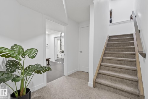 Hallway featuring carpeted flooring and a staircase with a wooden handrail - 13 Bilodeau Crescent, Beaumont, AB - Indoor Photo Showing Other Room