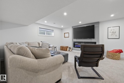 This living area features a built-in electric fireplace and media center, recessed lighting, and a window with blinds - 13 Bilodeau Crescent, Beaumont, AB - Indoor