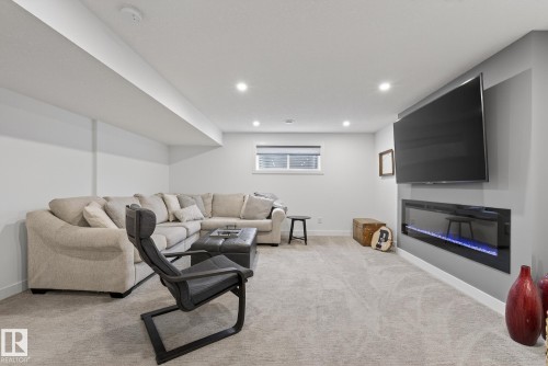 Living area with light-colored carpet, recessed lighting, and a wall-mounted electric fireplace - 13 Bilodeau Crescent, Beaumont, AB - Indoor With Fireplace