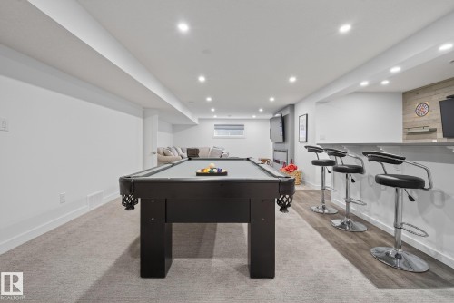 The spacious recreation room features a pool table, recessed lighting, and a bar area with four bar stools and wood-look flooring - 13 Bilodeau Crescent, Beaumont, AB - Indoor Photo Showing Other Room