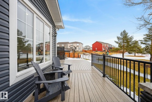 The property features a spacious deck with composite decking and black metal railings, offering views of the surrounding neighborhood and greenery - 13 Bilodeau Crescent, Beaumont, AB - Outdoor With Exterior