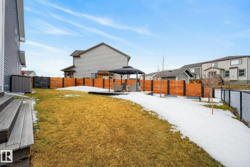 The property features a spacious backyard with a lawn and a privacy fence - 13 Bilodeau Crescent, Beaumont, AB - Outdoor With Exterior
