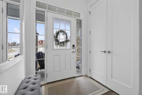 Welcoming entryway featuring a white paneled door with windowpanes and sidelights, an overhead transom window, and a light-colored floor mat - 13 Bilodeau Crescent, Beaumont, AB - Indoor Photo Showing Other Room
