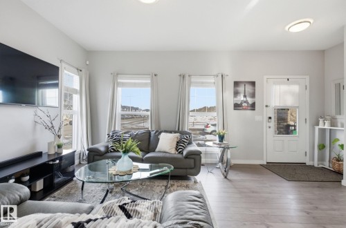 This living area features light-colored flooring and walls, with multiple windows providing natural light - 17498 76 St Nw, Edmonton, AB - Indoor Photo Showing Living Room