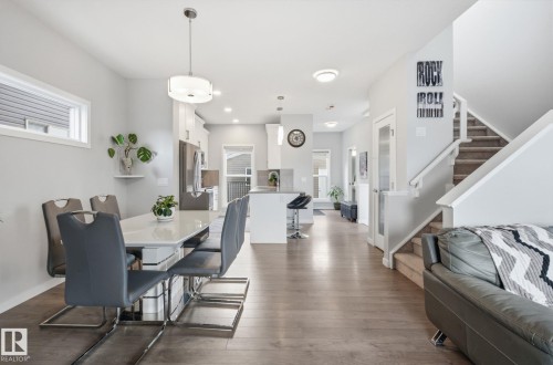 Open concept living space featuring hardwood floors, a dining area, and a staircase with carpeted treads - 17498 76 St Nw, Edmonton, AB - Indoor Photo Showing Dining Room