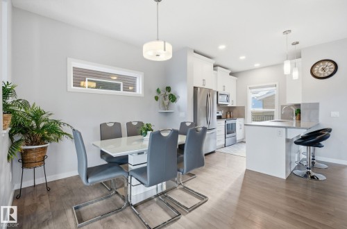 Open concept dining area and kitchen featuring hardwood flooring, recessed lighting, and stainless steel appliances - 17498 76 St Nw, Edmonton, AB - Indoor