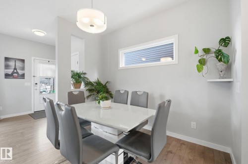 Dining area featuring hardwood floors, a modern chandelier, and a horizontal window providing natural light - 17498 76 St Nw, Edmonton, AB - Indoor Photo Showing Dining Room