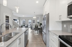 The kitchen features white cabinetry, stainless steel appliances, and a double basin sink set into granite countertops - 