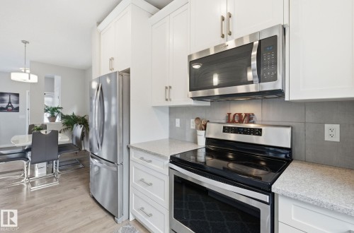The kitchen features white cabinetry, stainless steel appliances, and light-colored countertops - 17498 76 St Nw, Edmonton, AB - Indoor Photo Showing Kitchen With Upgraded Kitchen