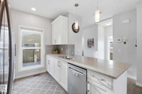 Kitchen featuring white cabinetry, a stainless steel sink, and light-colored countertops - 17498 76 St Nw, Edmonton, AB - Indoor Photo Showing Kitchen With Double Sink