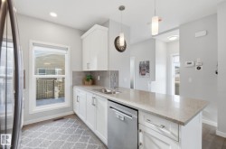 Kitchen featuring white cabinetry, a stainless steel sink, and light-colored countertops - 
