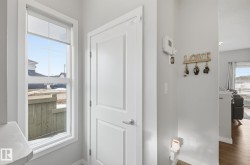 The entry features a white door, a window with a roller blind, and light gray walls - 