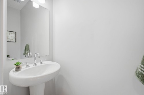 Pedestal sink with a polished chrome faucet and an illuminated mirror - 17498 76 St Nw, Edmonton, AB - Indoor Photo Showing Bathroom