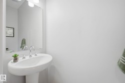 Pedestal sink with a polished chrome faucet and an illuminated mirror - 