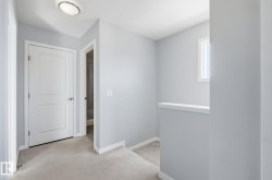 Hallway featuring light gray walls, white trim, and a window providing natural light - 